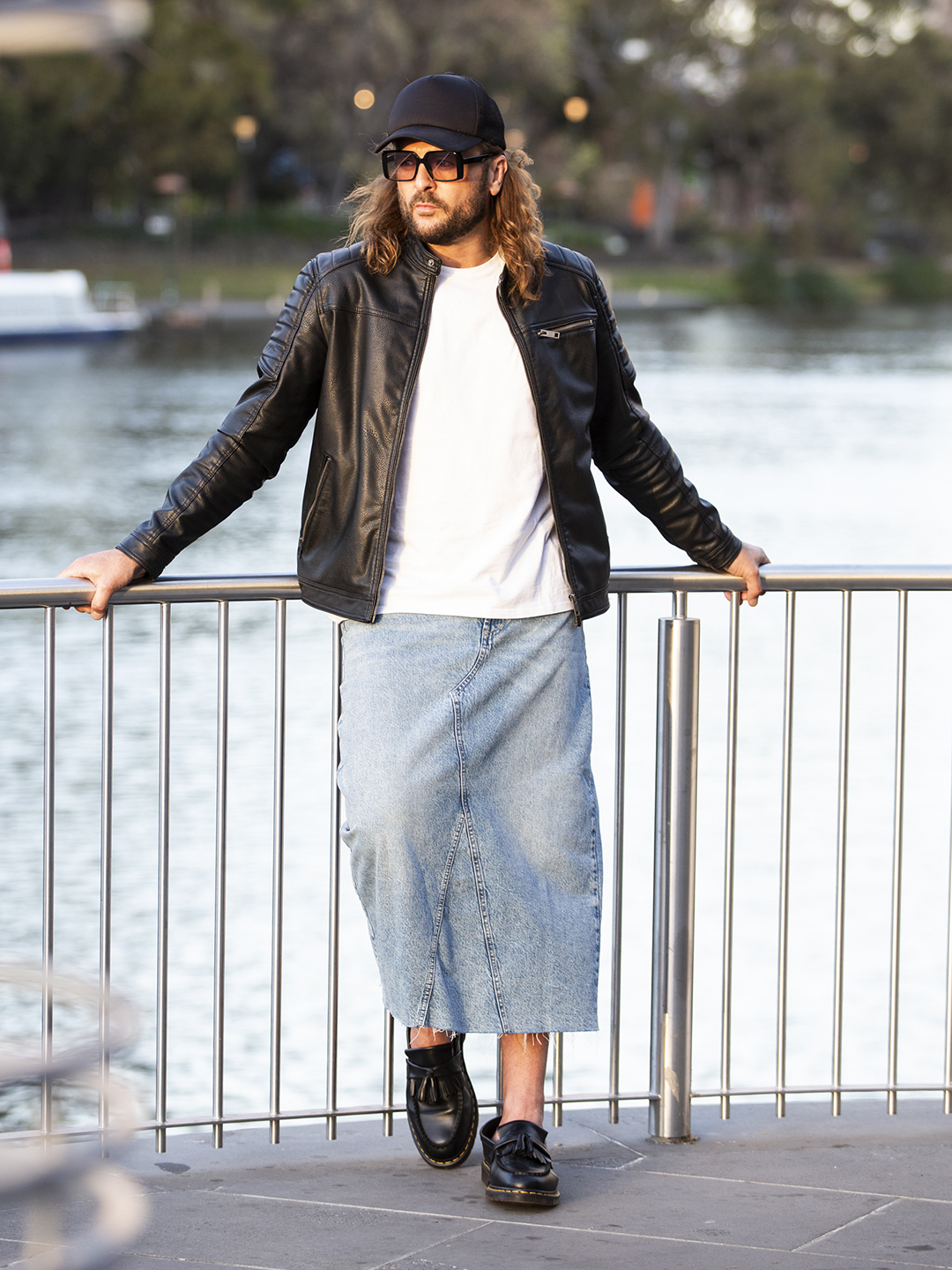 Brad wearing a leather jacket and denim skirt beside the water