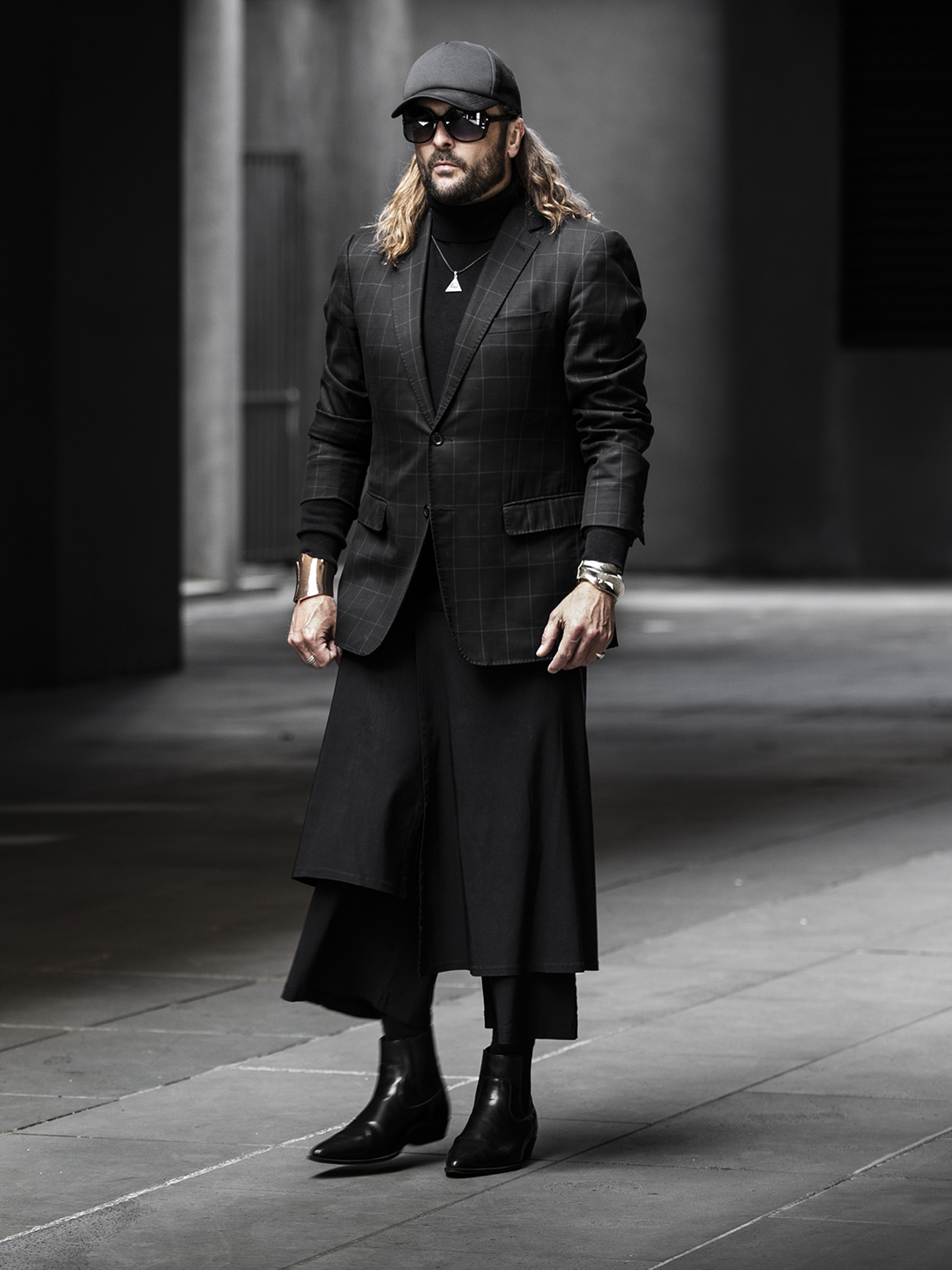 Brad in layered black tailoring, a long black skirt and boots